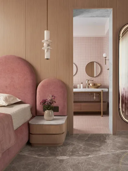 A glimpse from the kid's bedroom into the attached bathroom. The custom arched headboard in pink velvet continues the room's playful yet chic theme, while the marble-topped bedside table adds a touch of sophistication.