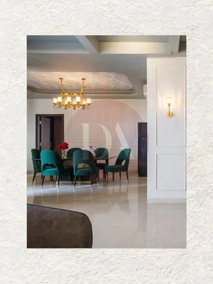 A closer look at the dining area where deep emerald chairs gather around the table. The design features a textured ceiling detail and a modern brass chandelier, creating a space that feels both luxurious and ready for conversation.
