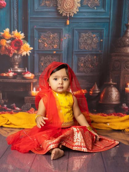 A beautiful portrait from a festive-themed shoot. This little girl in her traditional attire sits gracefully in a richly decorated setting.