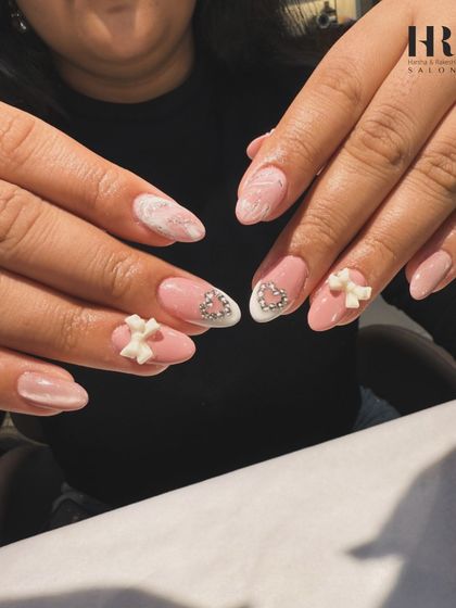 A closer view of this charming nail art. The combination of the soft bow, glittering heart, and subtle marble effect makes for a truly detailed and pretty manicure.