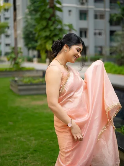 A candid shot of actress Aditi Prabhudeva in a delicate peach saree. Her joyful movement and the natural setting create a light and airy portrait.