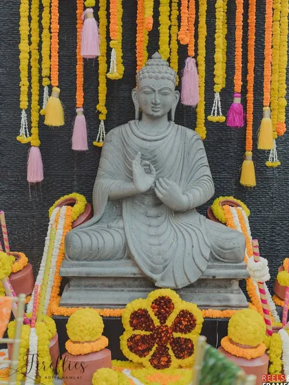 A statue of Buddha decorated with marigold garlands and tassels, creating a serene and spiritual corner at the event.