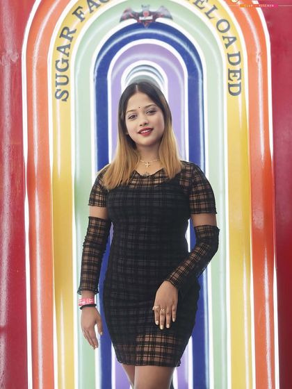 A guest posing at the colorful entrance of Sugar Factory.