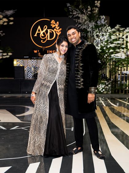 Posing on the dance floor, the couple's coordinated black and silver reception outfits exude glamour and sophistication, perfectly matching the event's elegant decor.