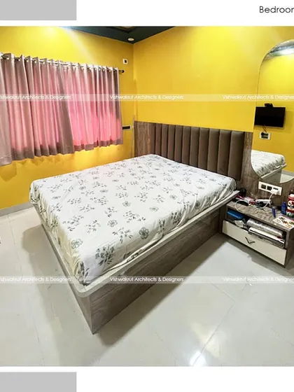 This bedroom uses a bold yellow accent wall to create a vibrant and energetic feel. The design is balanced with a wooden-finish headboard and wardrobe, adding warmth to the space.