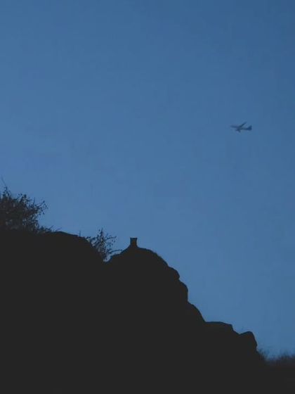 A leopard silhouette against the sky with a plane flying over, a shot from 2023 that captures the essence of our urban wildlife storytelling.
