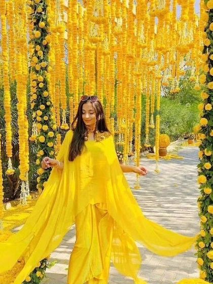 A beautiful shot of a bride walking through a passage decorated with hanging marigold garlands, creating an immersive floral experience.