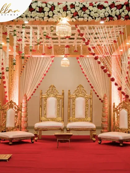 A royal mandap setup with grand seating for the couple and their families. The red and gold theme exudes opulence and tradition.