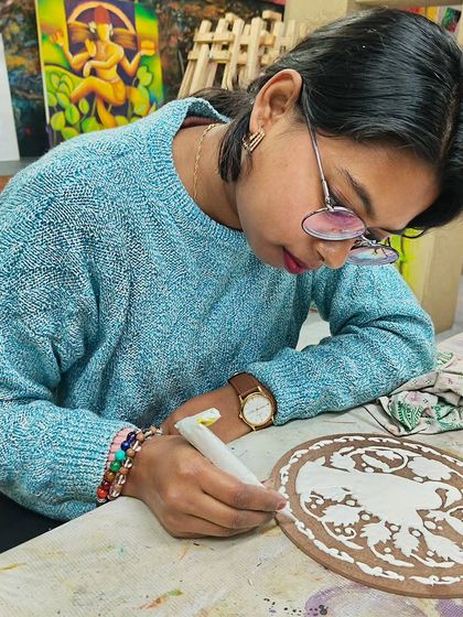 A student working on a ceramic plate, carefully painting a traditional design. Our classes cover various applications of painting skills.