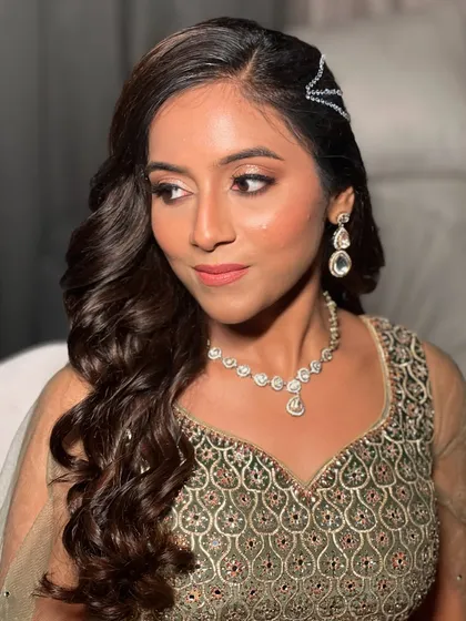 A side profile showing the elegant side-swept hair and sparkling makeup.