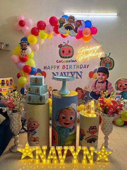 A Cocomelon theme perfect for a home celebration. This setup includes a circular backdrop, a neon sign, themed plinths, and marquee letters, making the most of an intimate space.