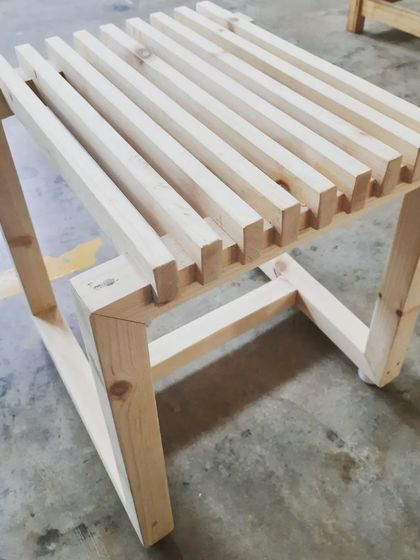 Another view of the slatted stool, showcasing the half-lap joinery used to connect the frame and the evenly spaced slats of the seat.