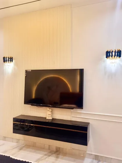 This bedroom features a sleek, floating TV console against a textured wall with elegant crystal wall sconces, creating a clean and sophisticated entertainment zone within the room.