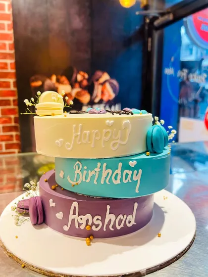 A unique three-tier cake with offset layers, personalized for a husband's birthday.