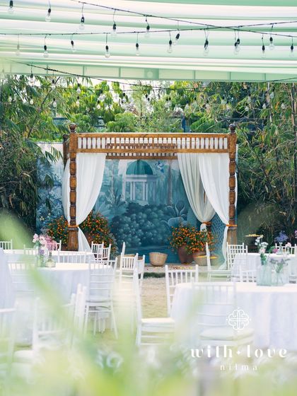 A simple mandap for a Varapuja ceremony, set against a lush bamboo grove. The hand-painted backdrop adds a touch of artistry and color.