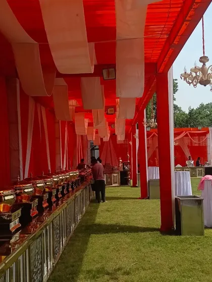 My services include setting up functional areas like catering. This is a long buffet line arranged under a covered tent with red and white fabric draping and chandeliers, ensuring all parts of your event are well-organized and presentable.