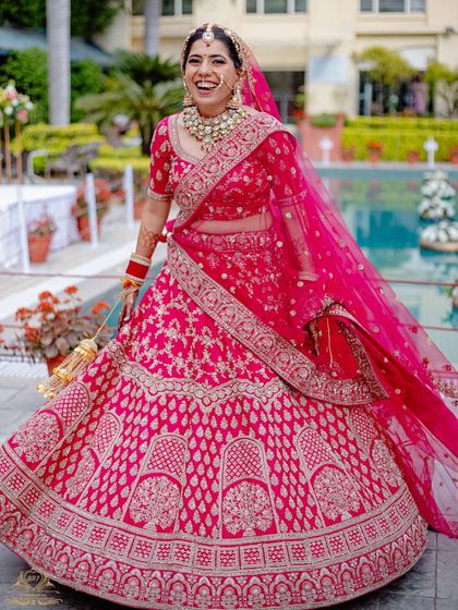 A bride's infectious laughter captured in a candid moment. Her vibrant pink lehenga and joyful expression are the highlights of this shot.