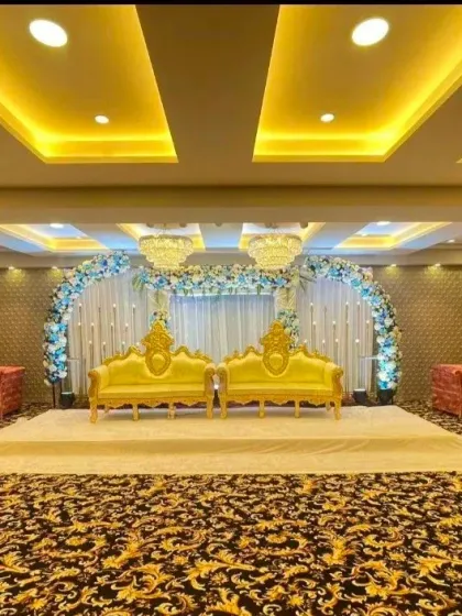 A bright and cheerful stage setup with yellow sofas against a blue and white floral arch. This decor at Palm Beach banquet hall is perfect for a daytime event or a vibrant theme.