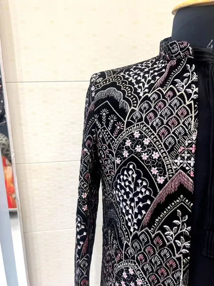 A side view of the black velvet jacket, highlighting the detailed embroidery that runs along the sleeves and body.
