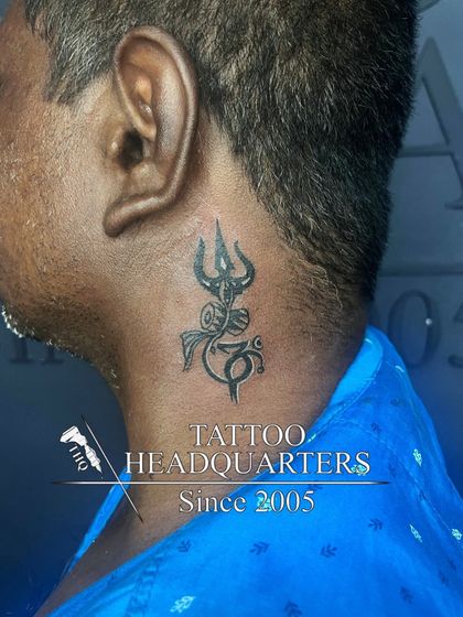 A neck tattoo combining the Om symbol with a Trishul, a popular design representing devotion to Lord Shiva.