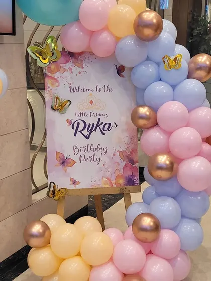 A close-up of the welcome sign for the butterfly party, surrounded by a custom balloon arrangement. The sign is personalized with the child's name and age.