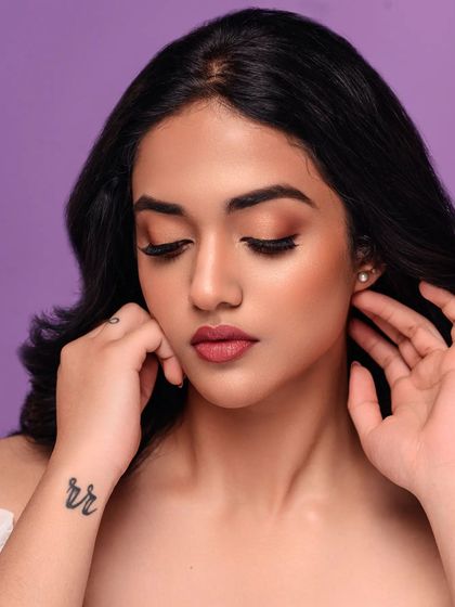 A soft and dreamy beauty portrait against a pastel purple background. The model's gentle expression and the clean lighting create a serene and beautiful image.