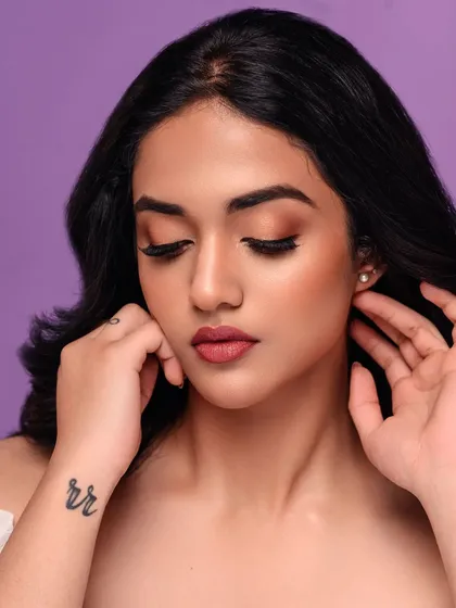 A soft and dreamy beauty portrait against a pastel purple background. The model's gentle expression and the clean lighting create a serene and beautiful image.