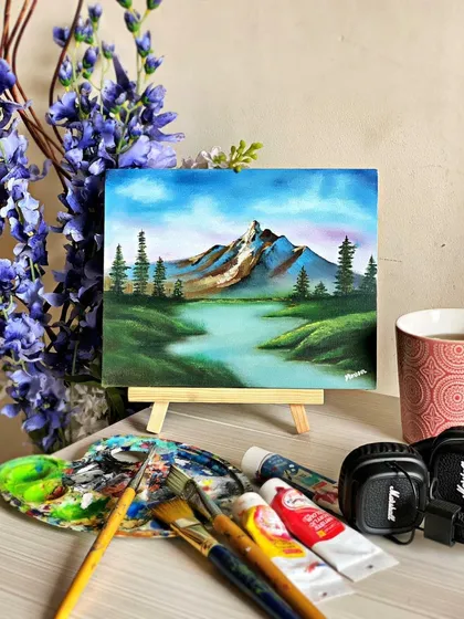 A finished landscape painting, capturing a quiet moment in nature. In my classes, I teach how to use acrylics to create depth and atmosphere, turning a blank canvas into a window to another world. All the supplies you see here are what we use in our sessions.