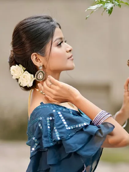 A side profile of the soft glam look, showing the elegant bun with white roses and the delicate details of the outfit.
