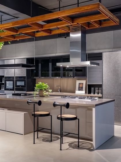 This industrial-chic display in Ahmedabad features concrete-look finishes, a stainless steel chimney, and a wooden ceiling detail, showcasing a more edgy, urban style.