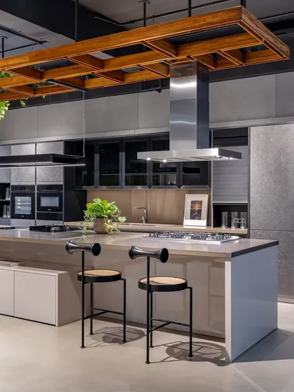 This industrial-chic display in Ahmedabad features concrete-look finishes, a stainless steel chimney, and a wooden ceiling detail, showcasing a more edgy, urban style.