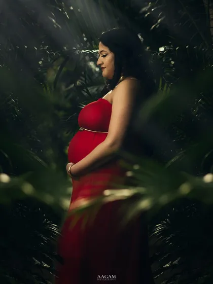 An outdoor maternity shot with a fine art feel. The rays of light filtering through the leaves create a magical, almost spiritual, atmosphere.