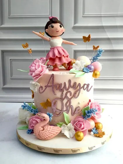 A graceful and delicate cake for a little ballerina's first birthday. It features a hand-sculpted ballerina figurine, sugar flowers, and a pink swan, creating a dreamy and enchanting theme.