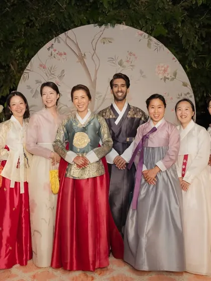 A wonderful group photo of the couple with their family and friends, all dressed in beautiful Hanbok. I coordinate attire and photo opportunities to capture the beauty of such cultural celebrations.