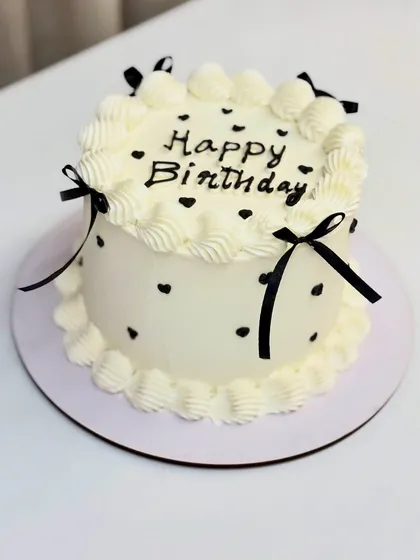 A sweet and simple vintage-style cake with black polka dots and delicate ribbons.