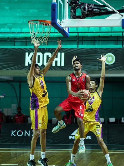 A basketball player goes for a layup, defended by two opponents. This action shot from the INBL showcases the high-stakes competition we help bring to life.