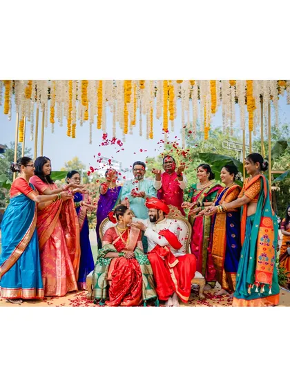 A wider view of the petal shower ceremony. This shot shows the entire family participating in the blessing, their colorful sarees creating a vibrant frame around the happy couple.