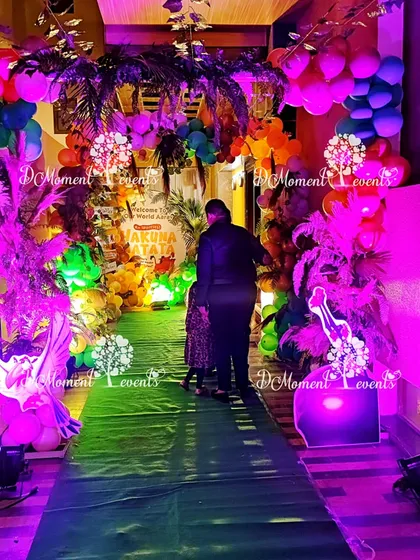 An "in the making" shot of the Lion King party entrance, with dramatic purple and green lighting highlighting the lush, jungle-like walkway.