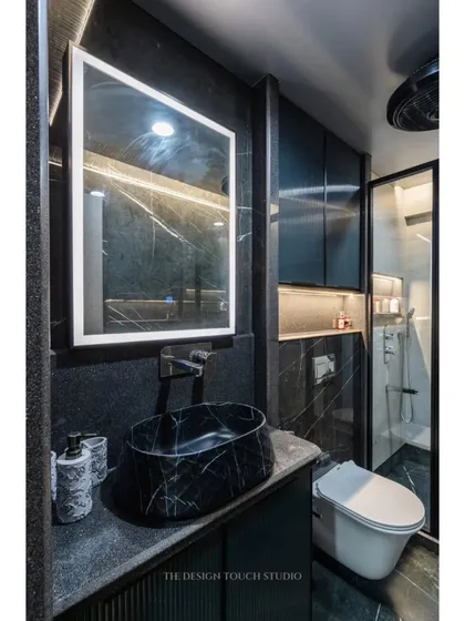 This bathroom design focuses on clean lines and high-quality materials. The black marble vessel sink and fluted vanity create a sophisticated and modern look.