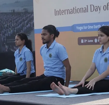 A moment of preparation and focus before beginning a seated forward bend as part of a stage demonstration.