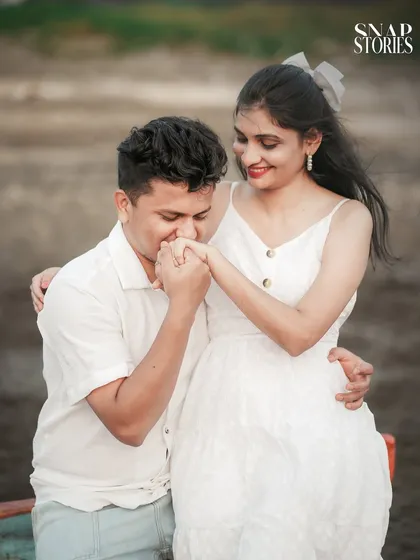 A classic romantic gesture captured during a casual pre-wedding shoot on the beach, showcasing the couple's sweet and gentle interaction.