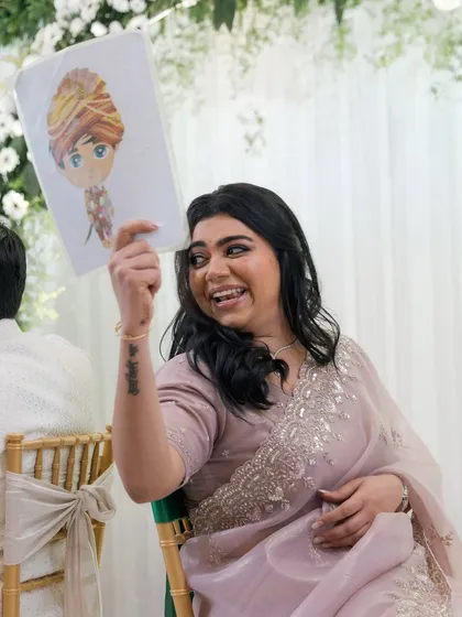 A bride playfully holds up a caricature of her groom during a wedding game.