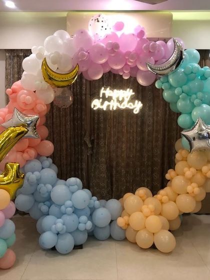 A dreamy pastel rainbow theme for a 4th birthday. The circular balloon arch is decorated with star and moon foil balloons, creating a celestial and soft look.