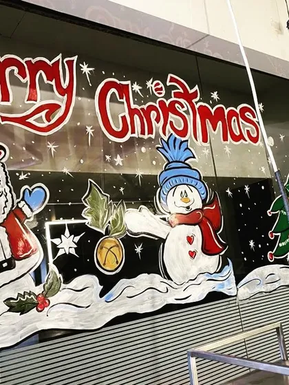 Getting a shop ready for the holidays with a cheerful Christmas scene. This temporary window painting features Santa Claus and a snowman, perfect for attracting customers and spreading festive cheer.