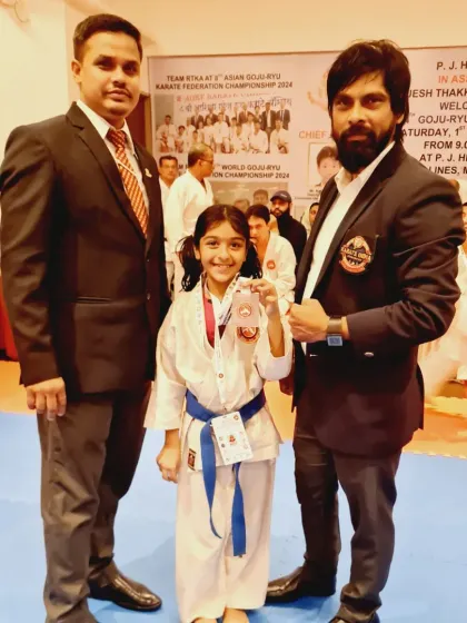 A young champion with her instructors. The guidance and support of our Senseis are instrumental in shaping our students into successful competitors.
