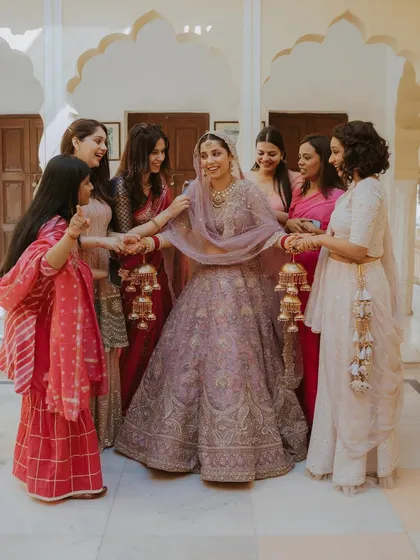 The bride is surrounded by her smiling bridesmaids during the Kalire ceremony, a moment of fun and friendship.