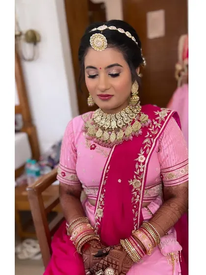 A beautiful bride in pink. For her wedding day, I created a classic look with shimmery eyes, a rosy lip, and a traditional bridal updo adorned with a matha patti.
