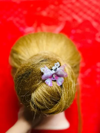 A simple and elegant bun accented with a delicate butterfly pin. Learning to place small, decorative accessories is just as important as creating the hairstyle itself.