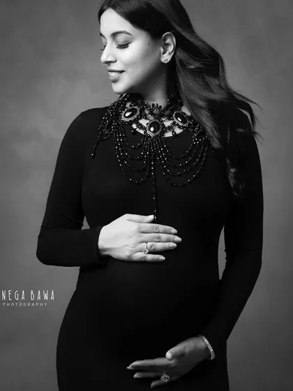 A beautifully styled solo portrait in black and white. The statement necklace adds a touch of personality and glamour to the classic black dress.