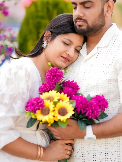 A tender embrace filled with warmth and comfort. The woman holds a vibrant bouquet while resting her head on her partner's chest, a beautiful, quiet moment from their pre-wedding session.